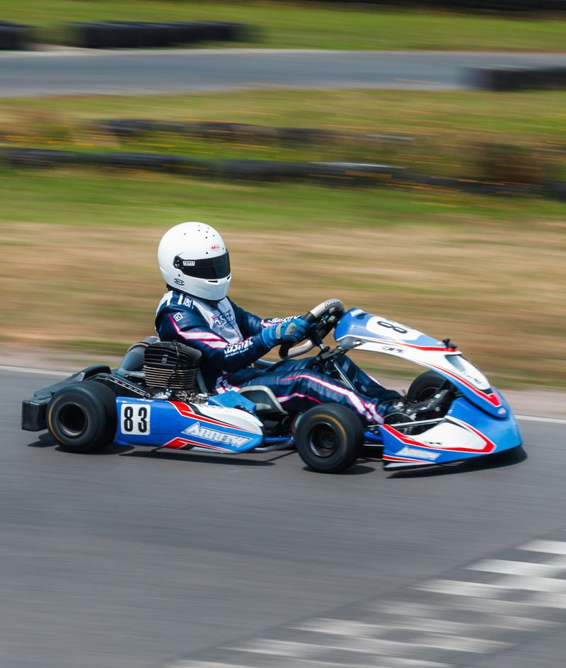 A driver in a blue race kart crossing the chequered line